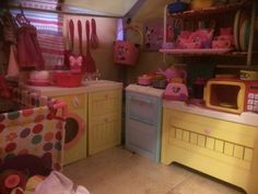 a kitchen filled with lots of pink and yellow furniture next to a stove top oven