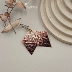 a pair of earrings sitting on top of a white plate next to a leafy plant