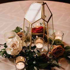 a table topped with candles and flowers on top of a white cloth covered tablecloth