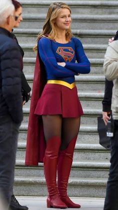 a woman dressed in a superman costume standing next to some stairs with her hands on her hips