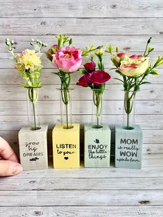 three vases with flowers in them sitting on a wooden table next to each other