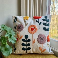 a pillow sitting on top of a yellow chair next to a potted green plant