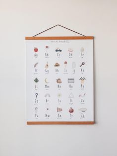 a wooden frame hanging on the wall displaying an alphabet poster