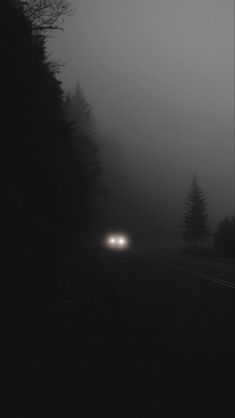 a car driving on a foggy road at night