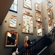 two women are standing on the stairs in front of some mirrors and staircase railings