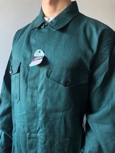 Workwear Pants / Work Coveralls / French Chore Pants / French Workwear / Size M-L This vintage coveralls in good unuse condition! - made in Belgium - color - green - 4 front pockets  - 2 cuff buttons - 7 buttons at front - material - sanforized cotton - fit size M/L (watch measurements) FLAT Measurements: Shoulders : 53cm Chest (underarm to underarm) : 60cm Sleeve : 67cm Length(back) : 92cm Waist : 47cm + elasticated waistband Inseam : 78cm Hem trousers : 25cm Model height and weight reference ( Fall Workwear Overalls With Patch Pockets, Cotton Overalls With Patch Pockets And Bib Front, Long Sleeve Cotton Overalls With Buttons, Cotton Overalls With Sleeves And Buttons, Utility Cotton Overalls With Patch Pockets, Utility Cotton Overalls With Buttons, Workwear Overalls With Patch Pockets, Solid Cotton Overalls For Workwear, Cotton Overalls For Workwear