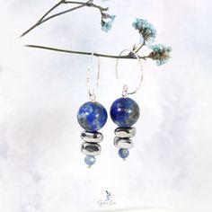 These elegant Lapis Lazuli bead stones dangle drop earrings feature a beautiful deep blue 12 mm Lapis Lazuli beads dangle drop and two painted silver Hematite stone beads, a faceted blue Kyanite tiny bead drop at the end. The beads are on solid 925 sterling silver eye pin, hooked on a diamond cut texture 925 sterling silver ear wire. Add these elegant Lapis Lazuli, Hematite and Kyanite beads dangle drop earrings to your everyday fine jewelry collection or as a gift for your loved one. Materials: 925 sterling silver, Lapis Lazuli, UV hematite, kyaniteDimensions: 1.84 x 0.46 in Jewelry Care: See more information about how to care for your jewelry here. Shipping Policy: Orders will be shipped within 1-3 business days. Economy shipping will take 7-14 days to arrive and standard shipping is 1- Agate Earrings With Natural Stones In Round Beads Shape, Elegant Agate Gemstone Bead Earrings, Agate Gemstone Bead Dangle Earrings, Blue Gemstone Bead Drop Earrings, Blue Gemstone Beads Drop Earrings, Metal Beaded Earrings With Faceted Beads For Gifts, Round Beads Earrings With Natural Stones For Jewelry Making, Dangle Earrings With Natural Stones And Czech Glass, Silver Lapis Lazuli Gemstone Earrings