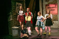 a group of young women standing on top of a stage