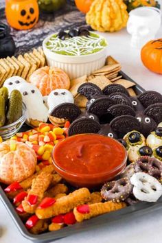 an assortment of halloween treats on a tray with candy and candies in the background