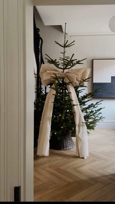 a small christmas tree in the corner of a room with white walls and wood flooring