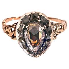 This rare and unusual 18th century ring is designed as a stylized heart and was created in 1760 ca. A heart shaped natural brown diamond is mounted in a closed silver setting. The brown diamond is surrounded by twelve grey rose diamonds in a sliver setting. The beautiful pierced ring shoulders are decorated with scroll work. The gold ring band is finely engraved. The silver heart has been riveted onto the gold ring. The gold back of the of the heart is engraved with fine lines evoking fern leave