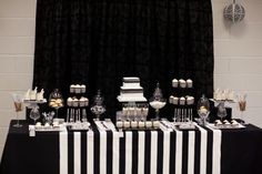 a black and white dessert table with cupcakes, cake, and candy bars