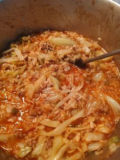 the food is being cooked in the pot on the stove top with a spoon inside