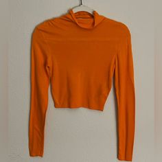 An Orange, Long-Sleeved, Turtle Neck Crop Top; Runched Design Across Both Shoulders, Runs Smaller; Never Worn Fitted Orange Tops For Work, Orange Stretch Long Sleeve Sweater, Orange Long Sleeve Stretch Sweater, Fitted Long Sleeve Orange Top, Casual Orange Tops For Layering, Fitted Orange Tops, Fitted Long Sleeve Top For Fall, Fitted Cropped Orange Top, Fitted Orange Cropped Top