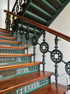 an iron and wood stair case with intricate designs on the railings, along with wooden handrails