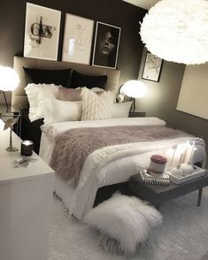 a white bed sitting in a bedroom next to two lamps and pictures on the wall