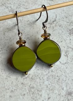 "green brass boho dangle earrings   czech glass earrings These round-ish, flat discs are opaque avocado green Czech glass with a Picasso coating on their edges. On top of each one sits a tiny brass disc and a light yellow glass saucer bead. Hook ear wires are antiqued brass. Length of earrings from top of ear wires is 1 1/2\". Glass discs measure 15mm diameter. You can enter my shop here: gypsydangles.etsy.com" Wood Beads Jewelry, Stone Bead Jewelry, Classy Earrings, Homemade Earrings, Earrings Handmade Dangle, Stacked Earrings, Earrings Inspiration, Square Earrings, Beaded Dangle Earrings