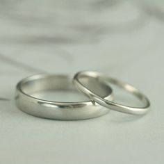 two silver wedding rings sitting on top of a white bed sheet in front of the camera