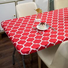 a red table with white chairs and a cake on it in front of a cabinet