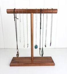 a wooden jewelry stand with several necklaces hanging from it's sides and on the other side