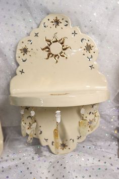 a white clock with sun and stars on it's face sitting on a table