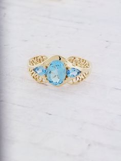 Vintage Blue Topaz filigree ring. Details: Size: US 9 ( can be sized ) Weight: 3.4 grams Primary stone: Blue Topaz Shape: Oval ( Appx. 8mm x 6mm ) Secondary Stone: Blue Topaz Shape: Pear Metal: 14k Yellow Gold Condition: Brand new! Inside of band is stamped and tested for '14k' gold. SIZING: Currently this ring is a size 9 but could be sized up or down for an additional small fee if desired by adding custom ring sizing to your cart upon checkout. Most sizing can be done within 1-3 days. PACKAGIN Classic Filigree Blue Topaz Rings, Fine Jewelry With Blue Topaz And Filigree Details, Classic Blue Topaz Filigree Ring, Elegant Filigree Ring With Blue Topaz Accent Stones, Elegant Filigree Ring With Blue Topaz Gemstone, Elegant Blue Topaz Filigree Ring With Accent Stones, Formal Filigree Blue Topaz Ring, Heirloom Blue Topaz Filigree Rings, Anniversary Filigree Ring With Blue Topaz And Accent Stones