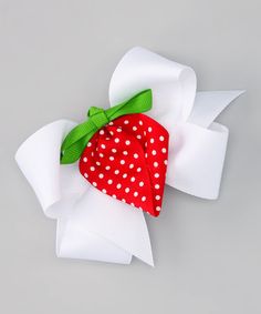 a red strawberry with white polka dots and green ribbon on a gray background, tied in a bow