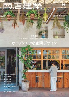 a woman standing in front of a counter with potted plants hanging from the ceiling