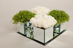 white roses and greenery in mirrored cube vases