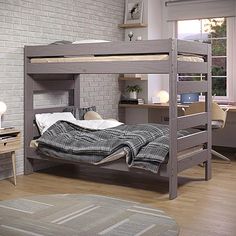 a bedroom with a bunk bed next to a desk and chair in front of a brick wall