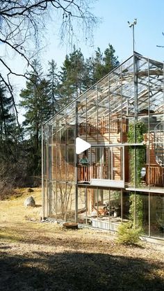 a house that is in the middle of some trees and grass with a glass roof