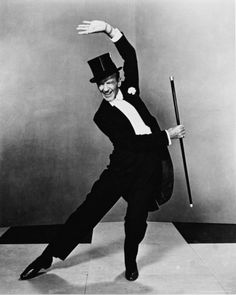 a man in a suit and top hat is dancing with a cane on the floor