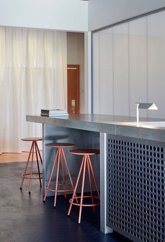 two stools are sitting at the bar in this modern kitchen with stainless steel countertops