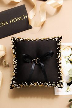 a black ring pillow on top of a table next to some flowers and a card