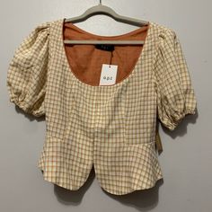 a brown and white checkered top hanging on a hanger