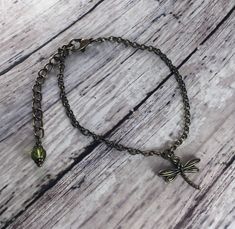 This simple Goblincore inspired bracelet features a tiny 15x19mm antiqued brass toned dragonfly charm. It is all tied together with antique brass toned toned chain and an antiqued brass toned lobster clasp. This bracelet is measures 6 1/2 inches and is extendable up to 8 inches. At the end of the extender chain, a 6mm olive green faceted glass bead dangles. I love this tiny accent- the color pairs well with the forest, moss themed dragonfly! Feel free to convo me if you would like to customize a Adjustable Brass Charm Bracelet, Adjustable Brass Charm Bracelet For Gifts, Antique Adjustable Charm Bracelet Gift, Bronze Metal Bracelets With Lobster Clasp, Adjustable Brass Bracelet With Lobster Clasp, Adjustable Brass Bracelets With Lobster Clasp, Bronze Metal Bracelet With Lobster Clasp, Handmade Adjustable Brass Charm Bracelet, Handmade Brass Charm Bracelet