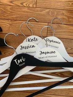 four white hangers with black and white name tags on them, sitting on a wooden floor