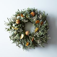 a wreath with oranges and greenery hanging on the wall