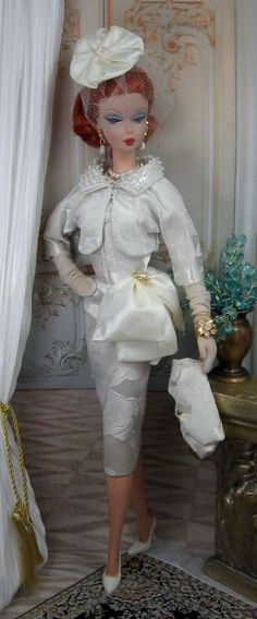 the doll is wearing a white dress and hat