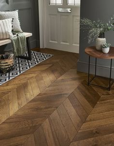 a living room with grey walls and wood floors, two planters on the end table