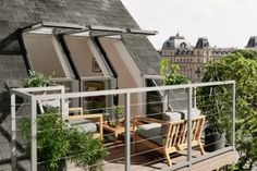 a balcony with chairs and tables on the top floor next to an open roof window