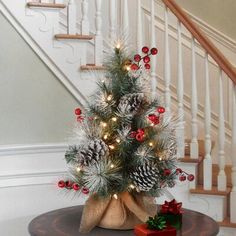 a small christmas tree sitting on top of a table next to a stair banister