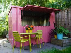 a pink shed with green chairs and tables