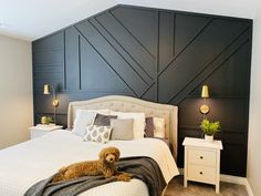 a dog laying on top of a white bed in a room with black paneled walls