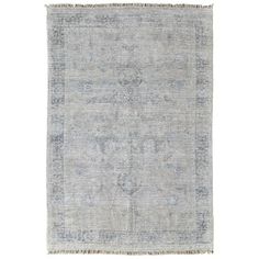 an antique rug with faded blue and grey colors on the bottom, including fringes