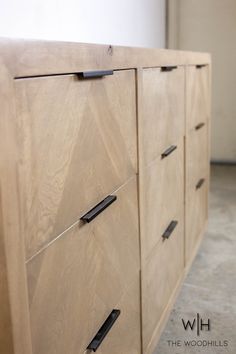 a close up of a wooden dresser with black handles