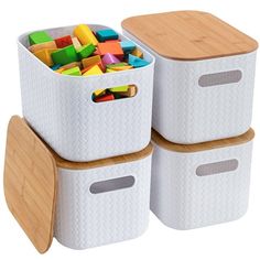 two white storage bins with wooden lids and handles filled with colored blocks in them