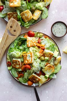 two plates filled with salad on top of a white table next to lemon wedges