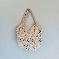 a crocheted bag hanging on a wall with a blue background in the foreground