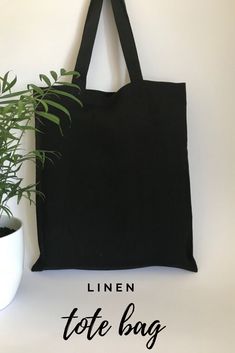 a black tote bag next to a potted plant with the title linen tote bag